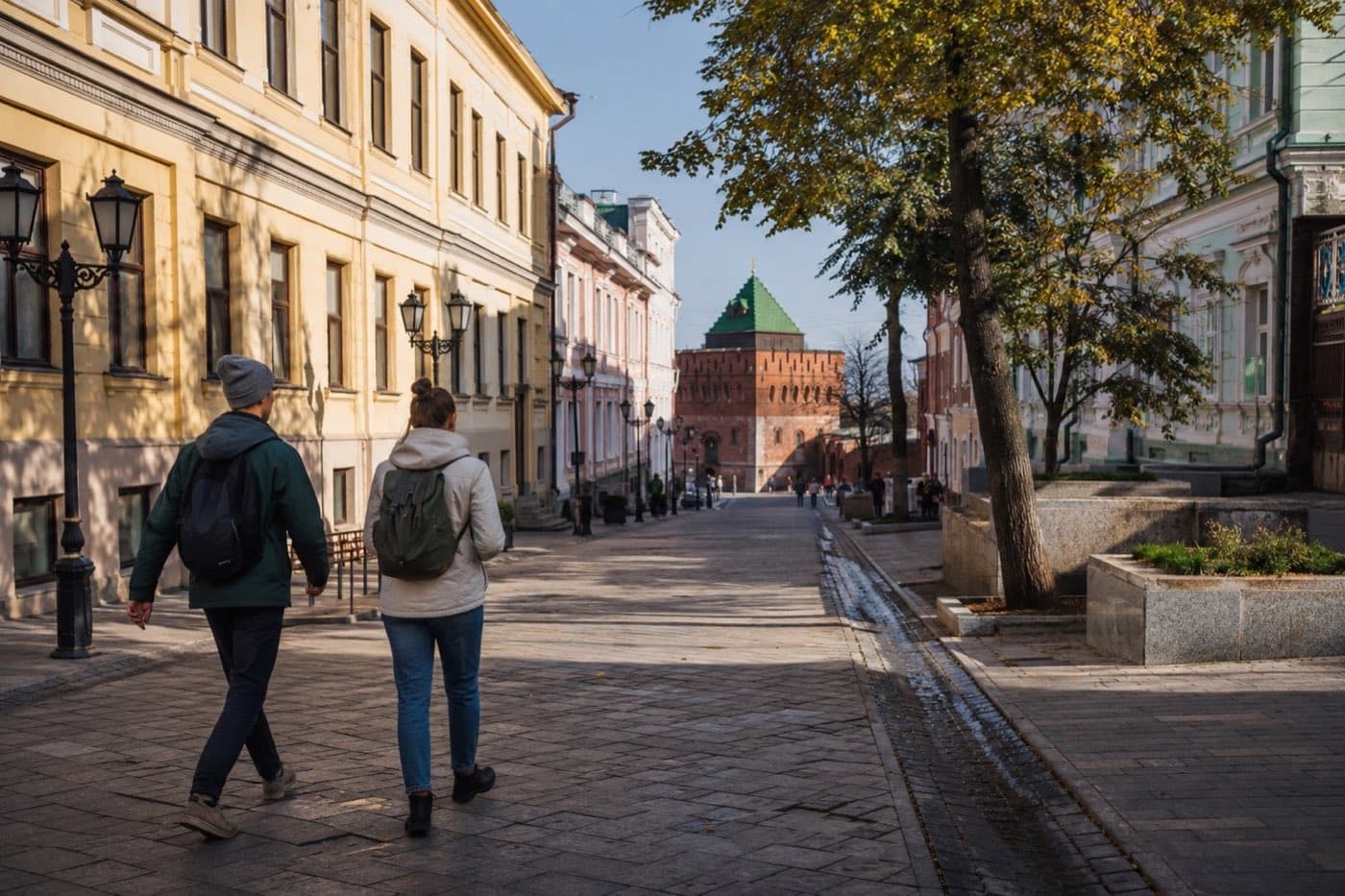 Путешественники идут по исторической улице Нижнего Новгорода к кремлёвской башне