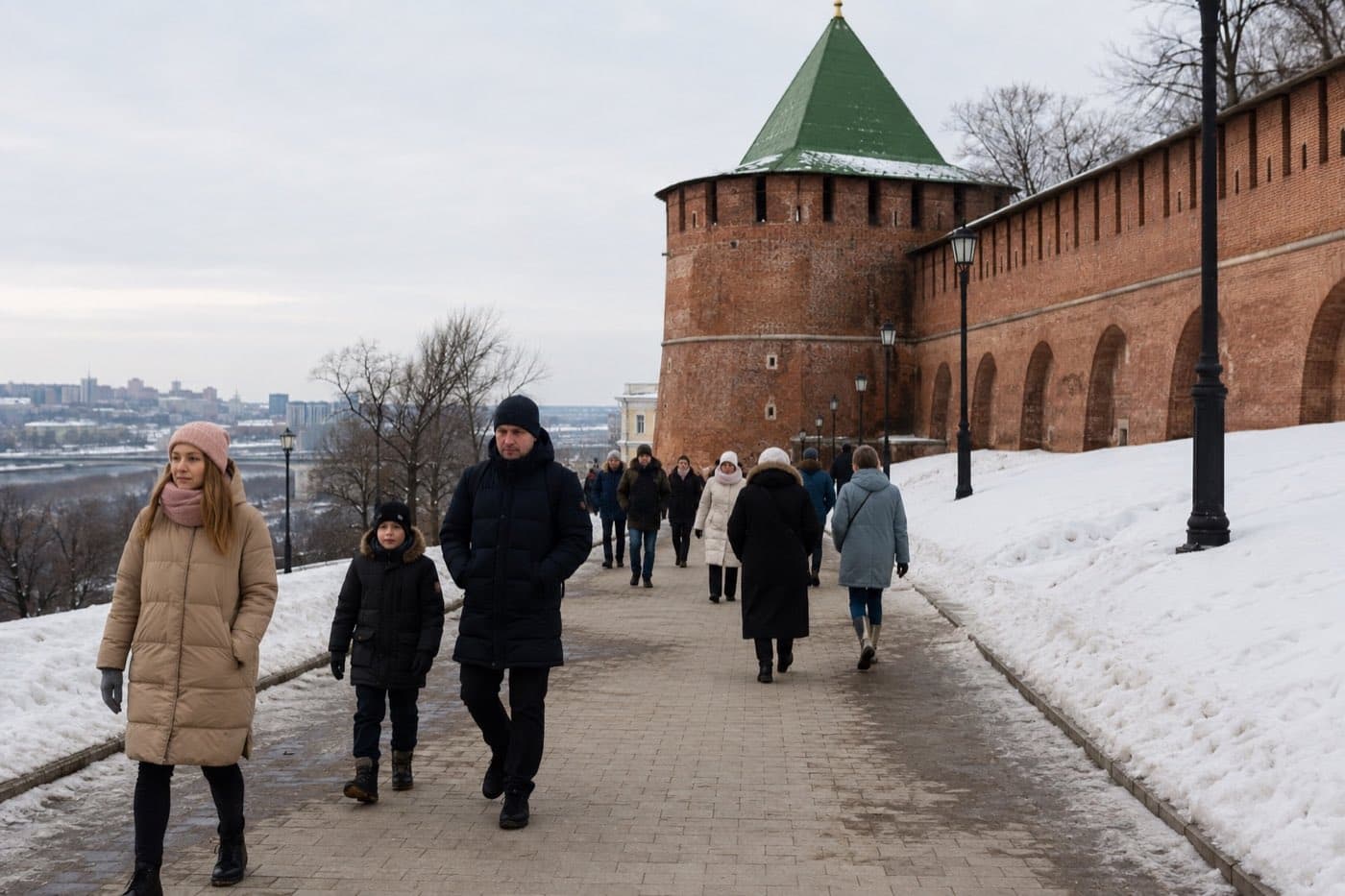 Посетители идут по расчищенной дорожке вдоль заснеженной стены Нижегородского кремля
